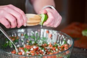 squeezing fresh lime juice into pico de gallo.