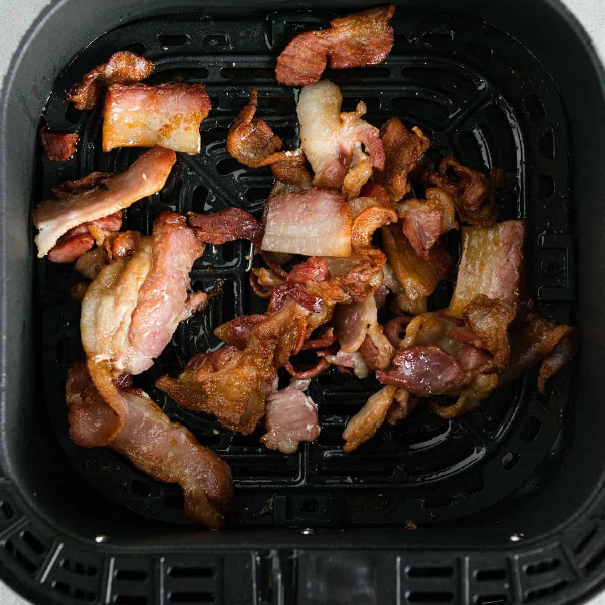 Partly cooked bacon in an air fryer basket