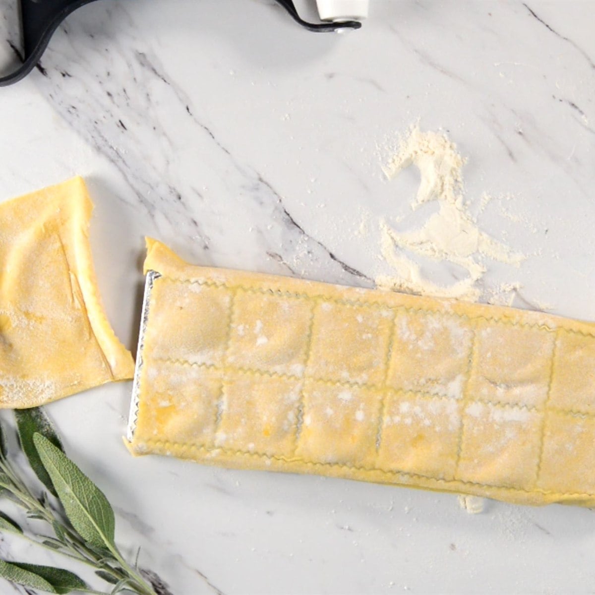 a second sheet of pasta dough laid over the filled ravioli mold