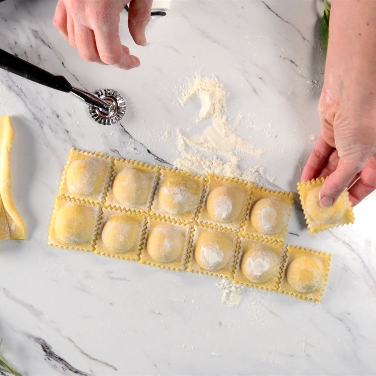 homemade butternut squash ravioli being lifted out of the ravioli mold