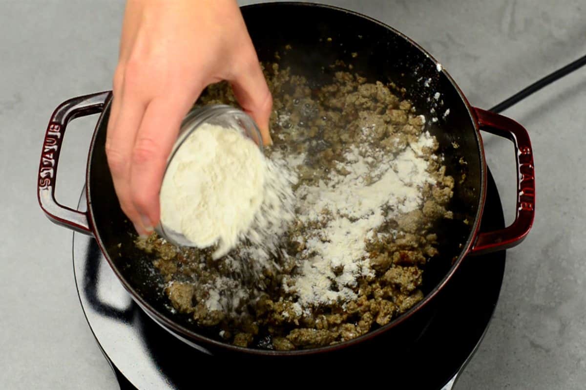 adding flour to cooked ground breakfast sausage.