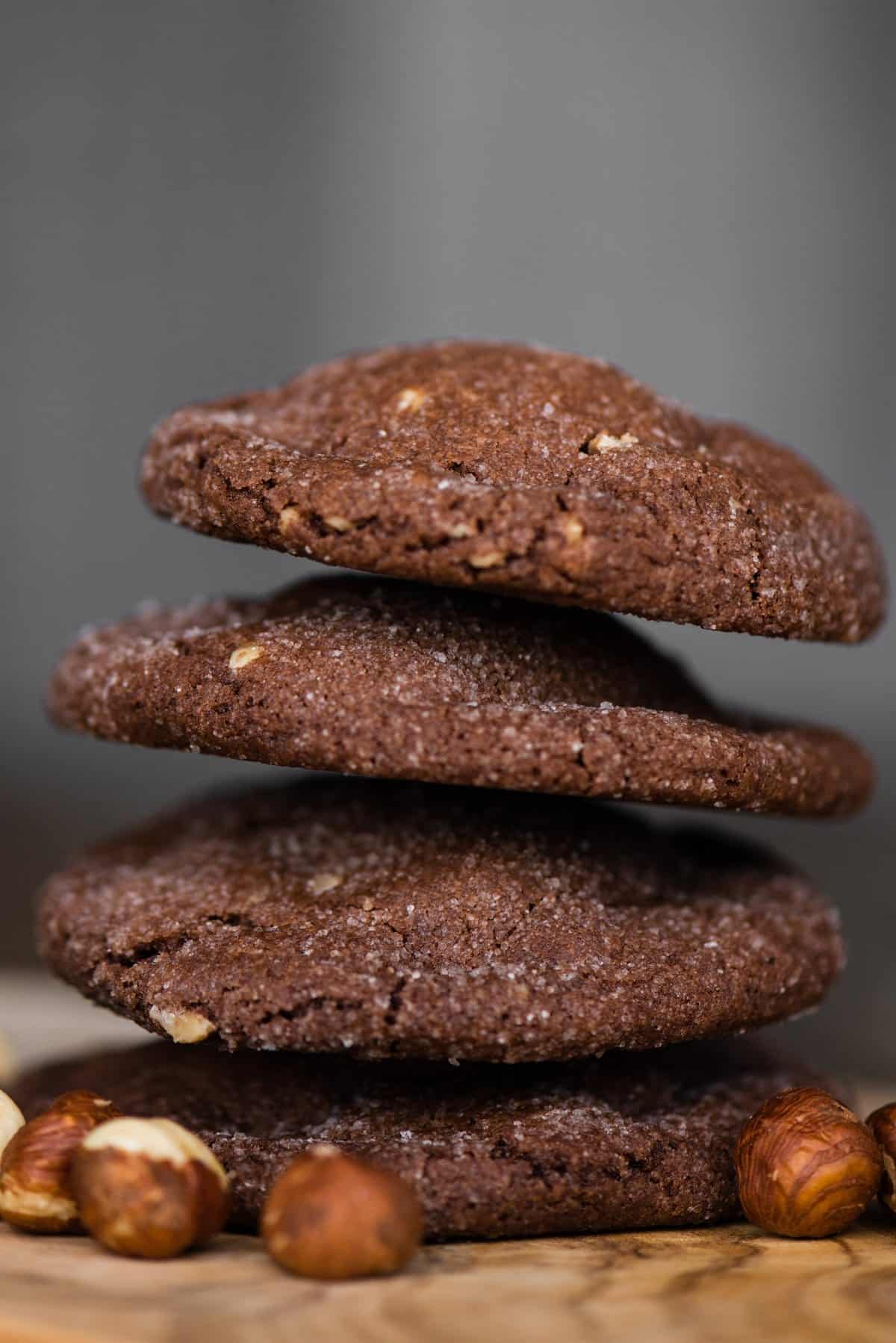 Tall stack of four Nutella stuffed chocolate cookies with hazelnuts at the base