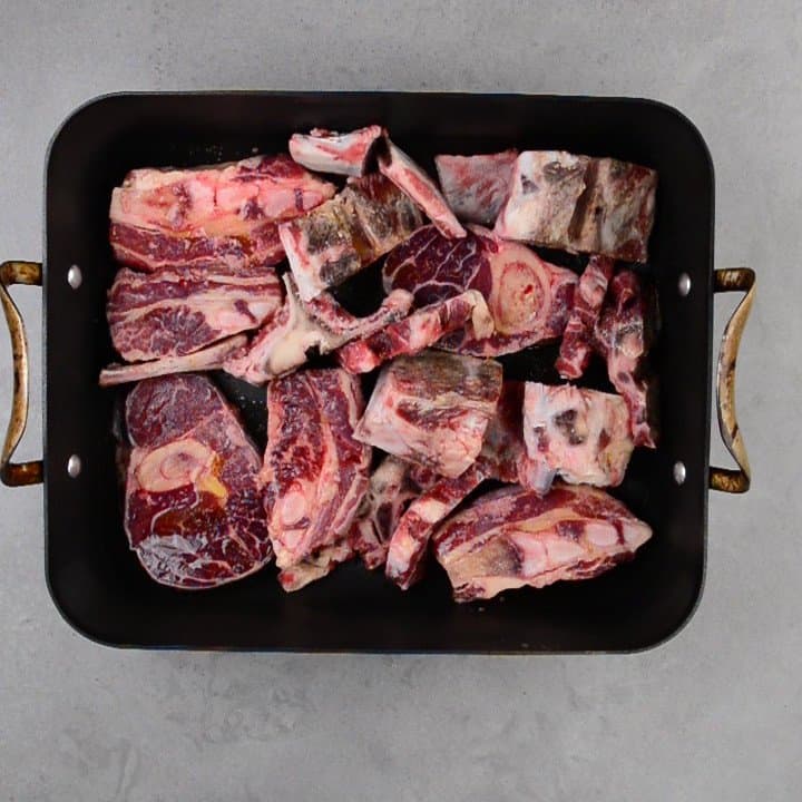 raw beef bones in a roasting pan.