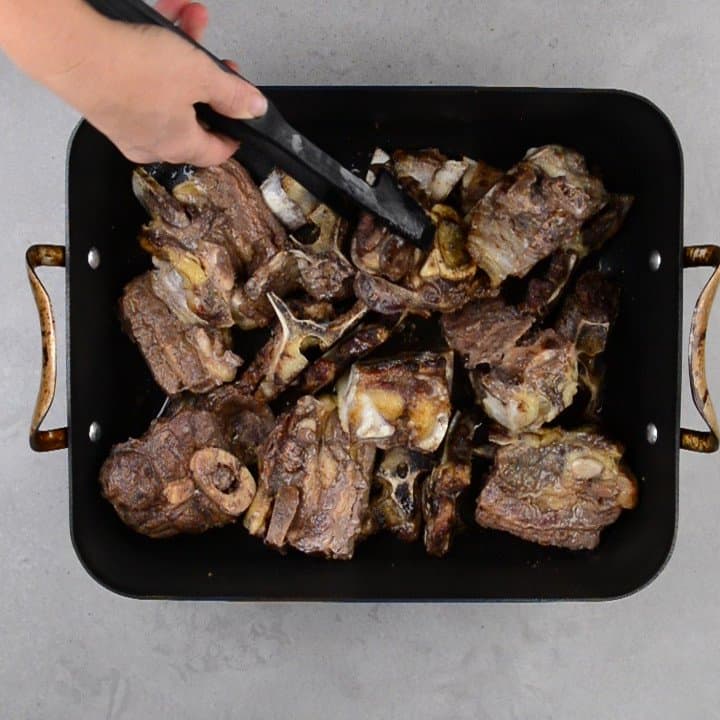 flipping roasted beef bones with tongs.