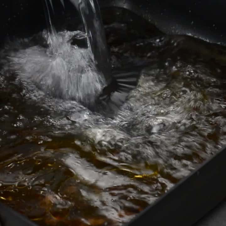 pouring water into the roasting pan to loosen the browned bits.