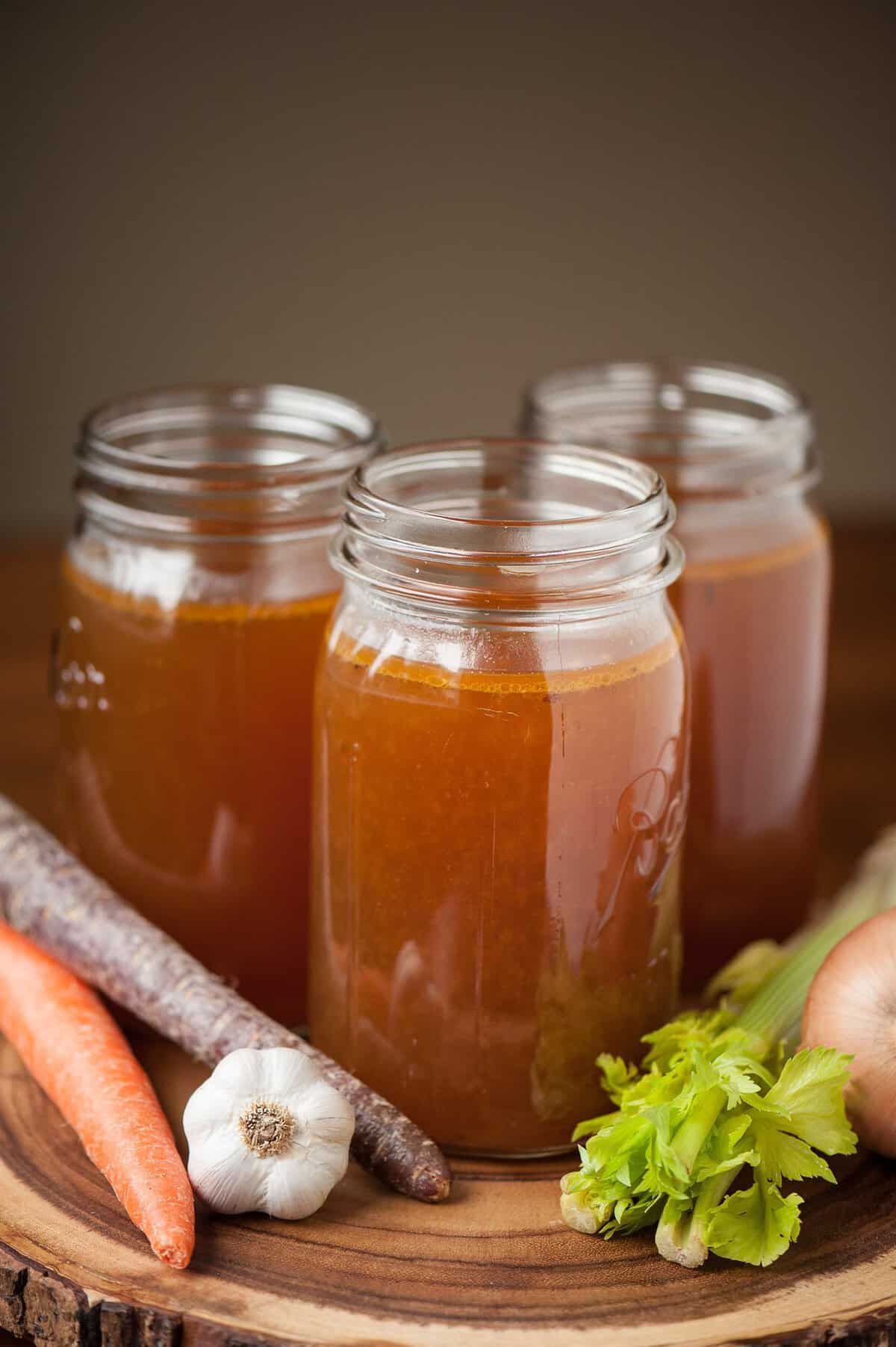 three jars of roasted beef bone broth with carrots, garlic and celery.