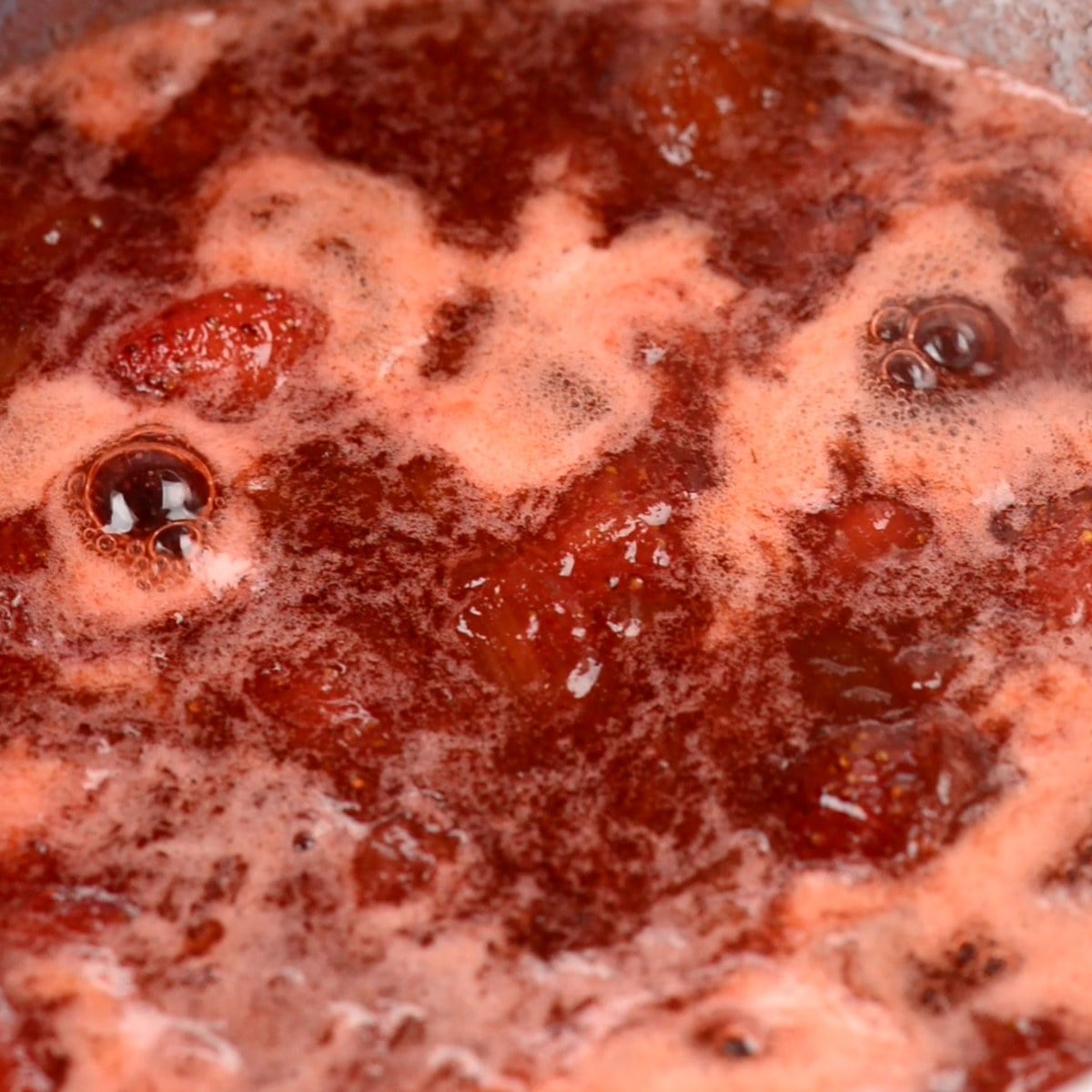 strawberry rhubarb jam bubbling as it cooks down and thickens