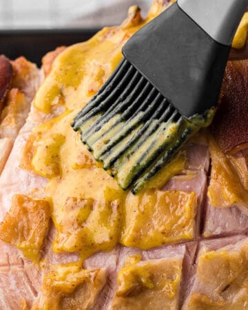 brushing 3-ingredient pineapple mustard brown sugar glaze on ham.