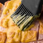 brushing 3-ingredient pineapple mustard brown sugar glaze on ham.