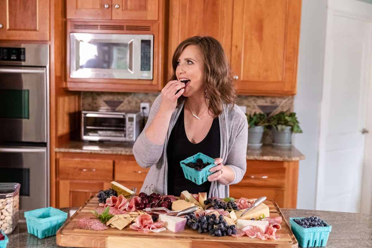 krissy allori eating berries while making a charcuterie board