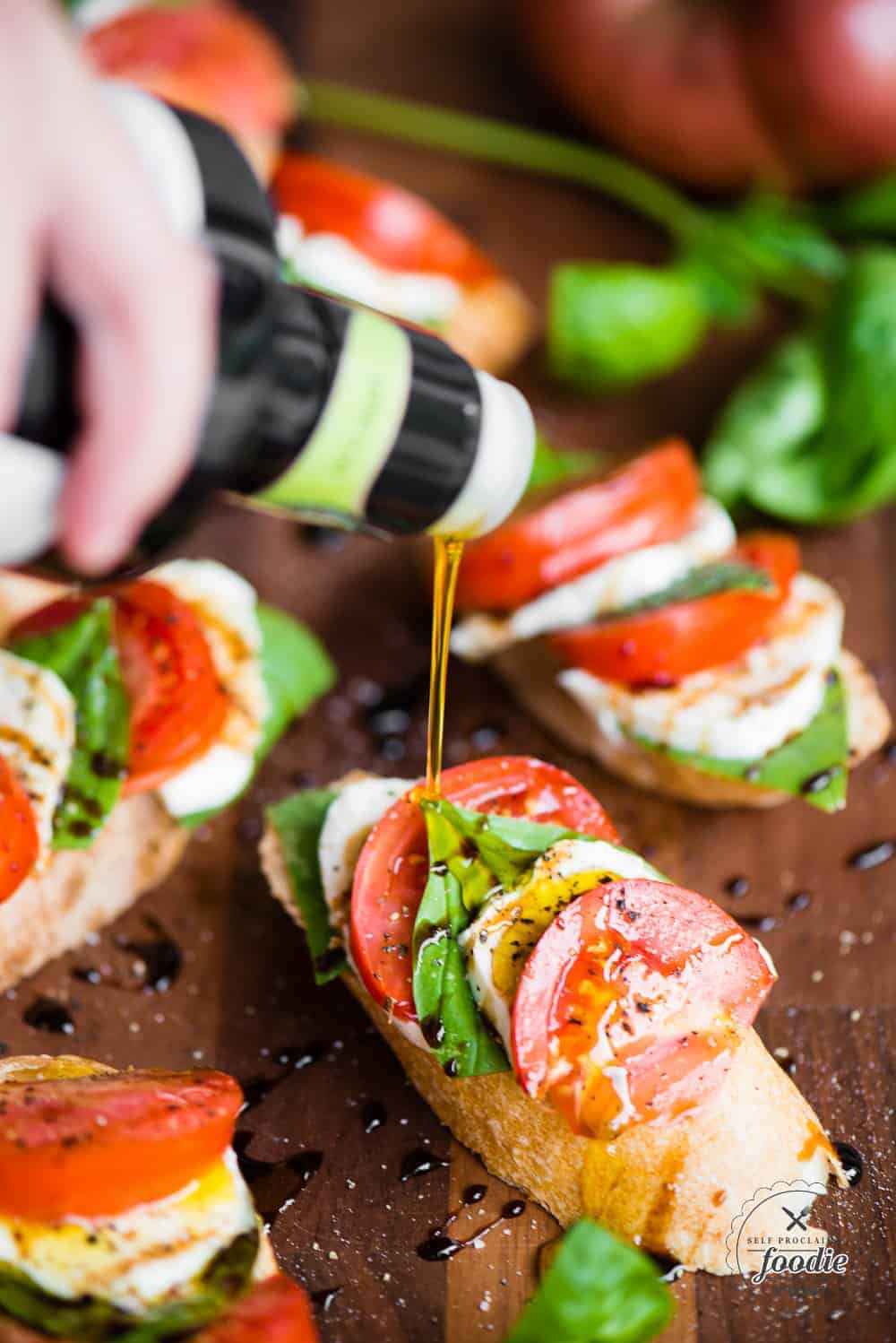 caprese bruschatta with olive oil being poured