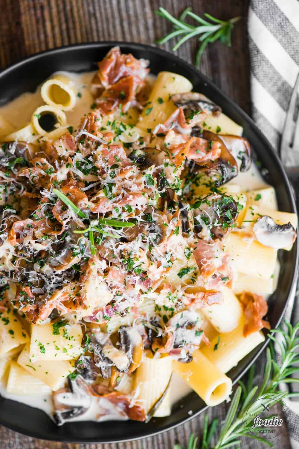  a plate of creamy rigatoni pasta with mushrooms and prosciutto