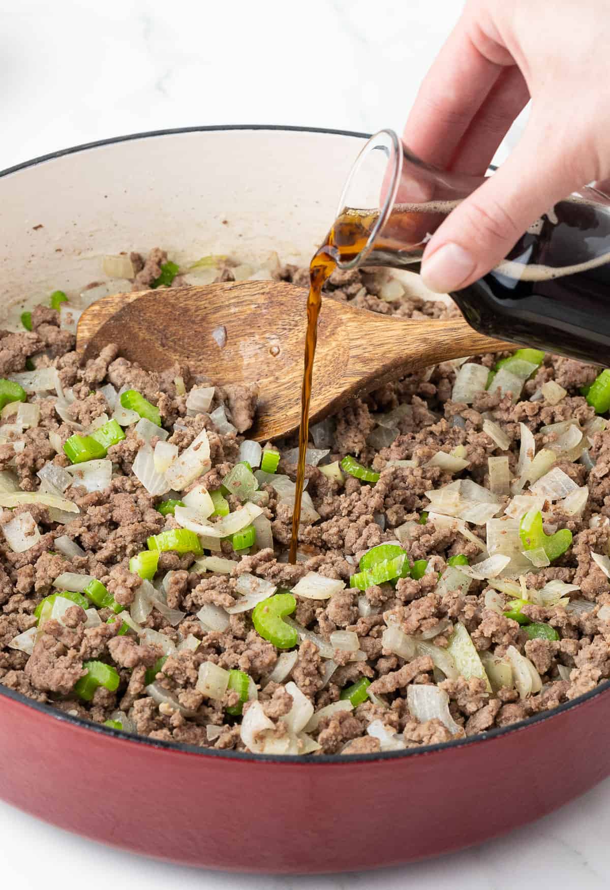 pouring Worcestershire sauce onto ground beef