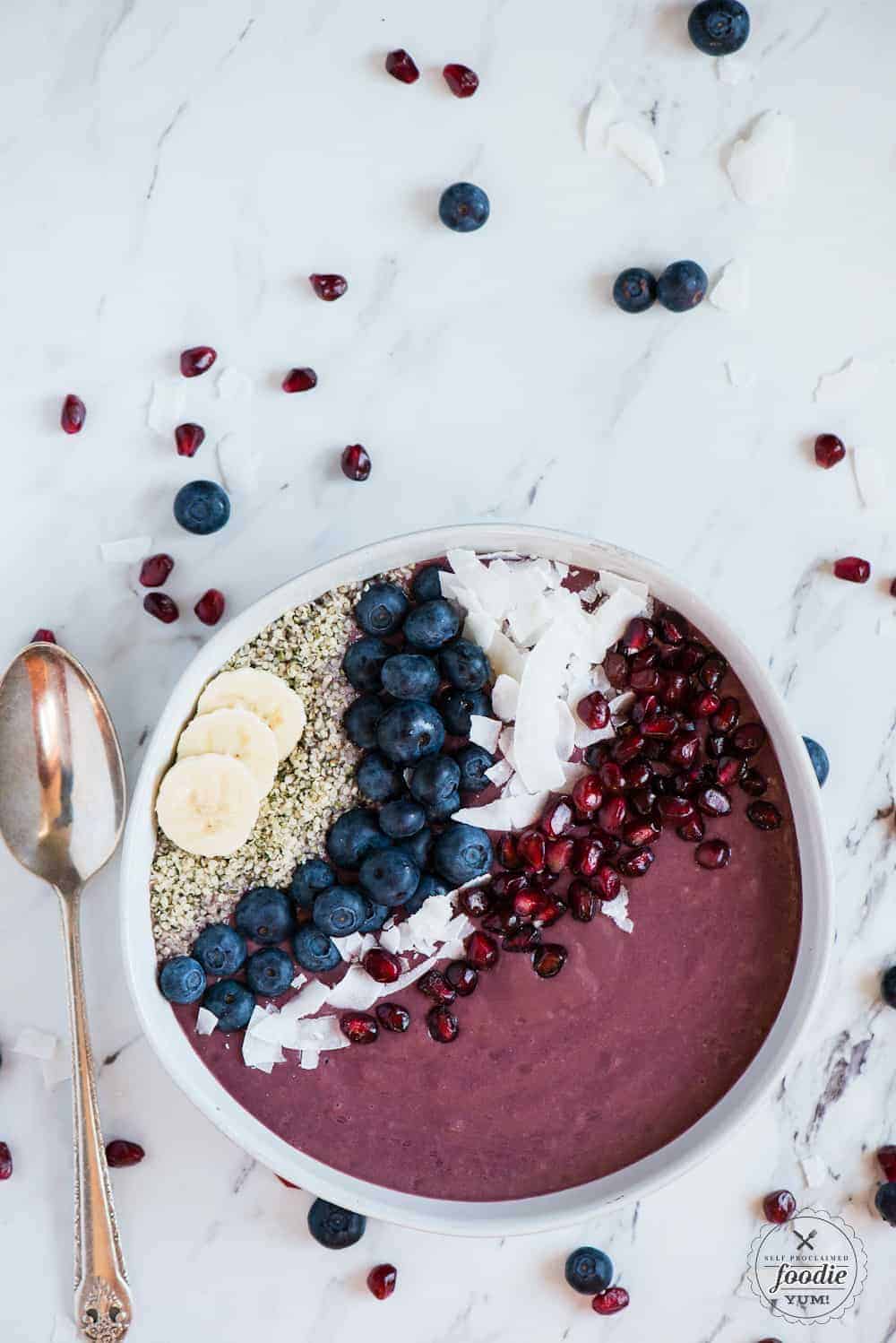 vegan acai bowl topped with coconut, blueberries, hemp heart, coconut and pomegranate