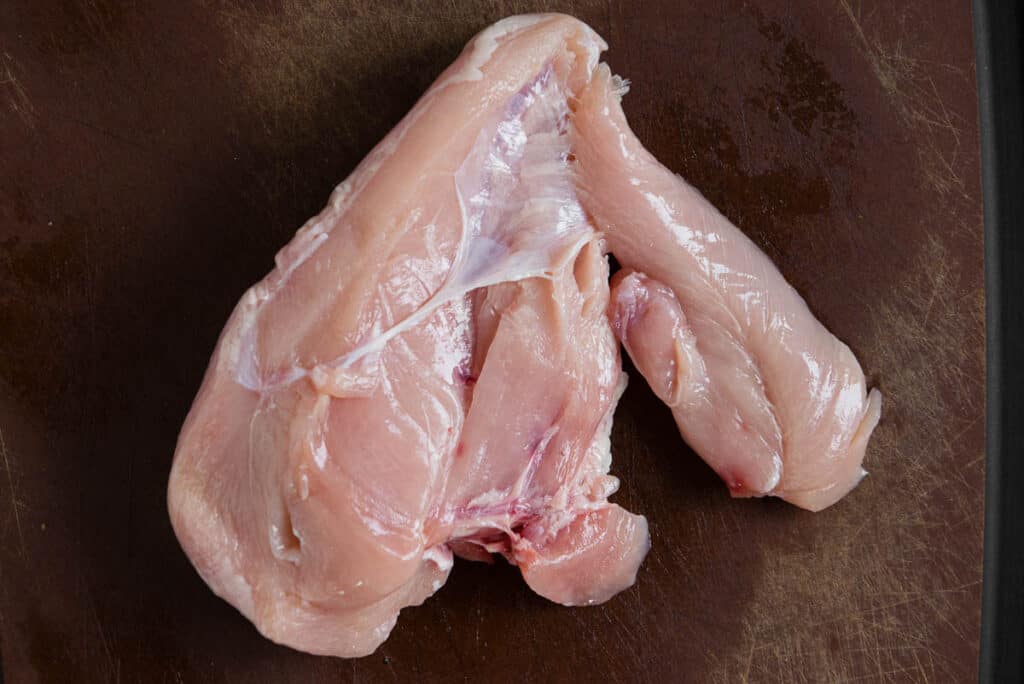 whole boneless skinless chicken breast on cutting board