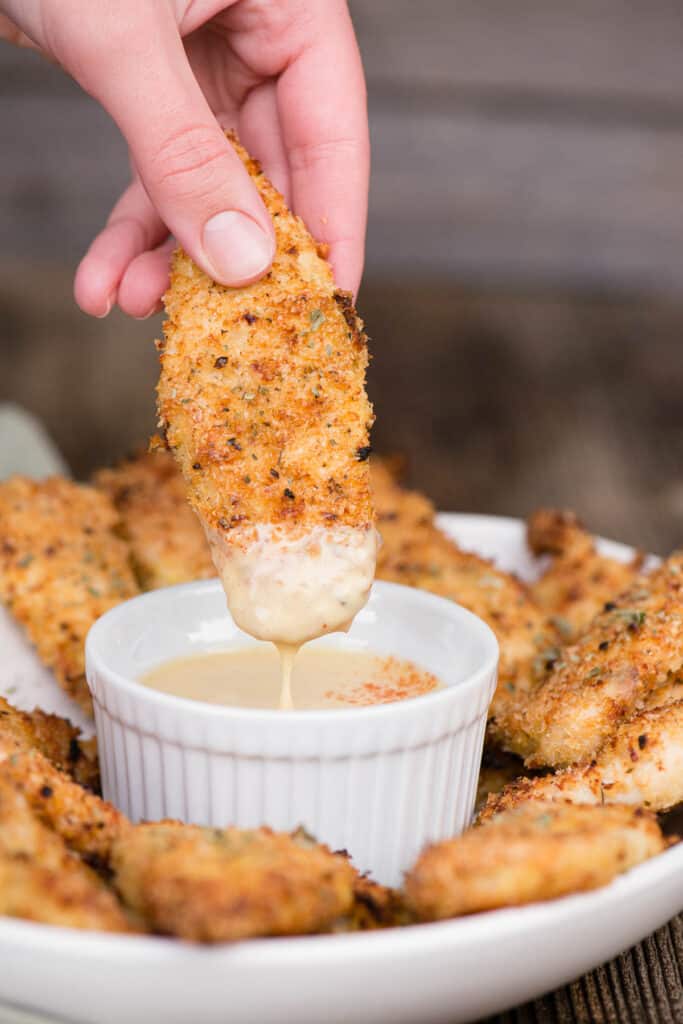 dipping a chicken tender into honey mustard sauce