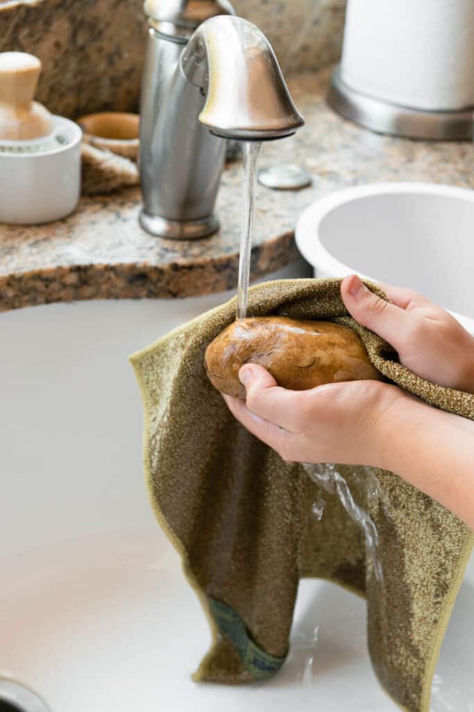 scrubbing a russet potato under running water