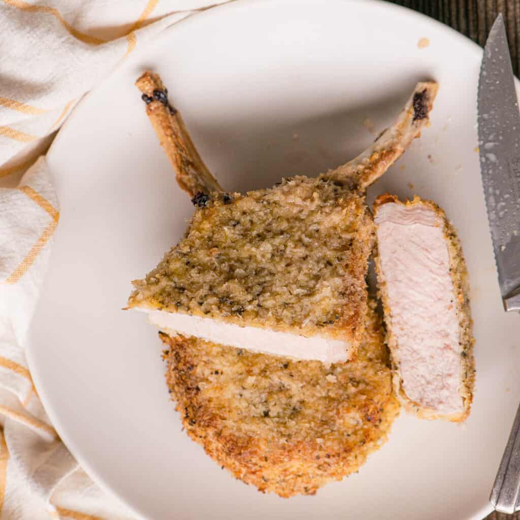 two breaded air fryer pork chops on plate.