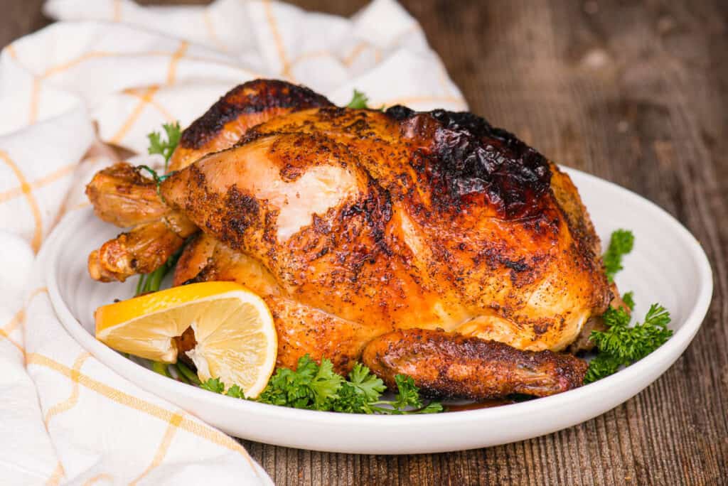 Air Fryer Whole Chicken on platter with lemon and parsley