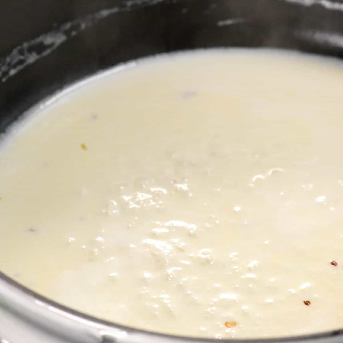 Alfredo sauce bubbling in saucepan.