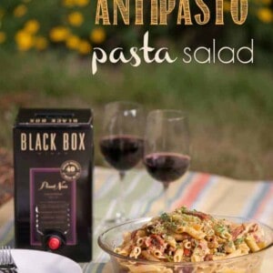 pasta salad  in bowl with box of wine and two wine glasses