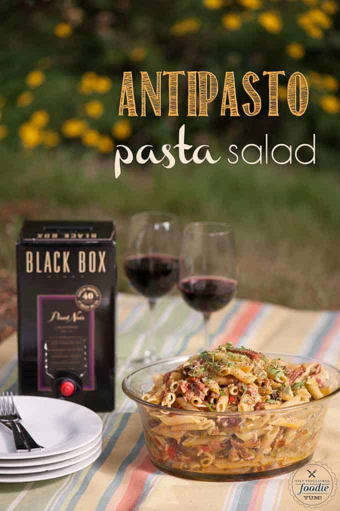 pasta salad  in bowl with box of wine and two wine glasses