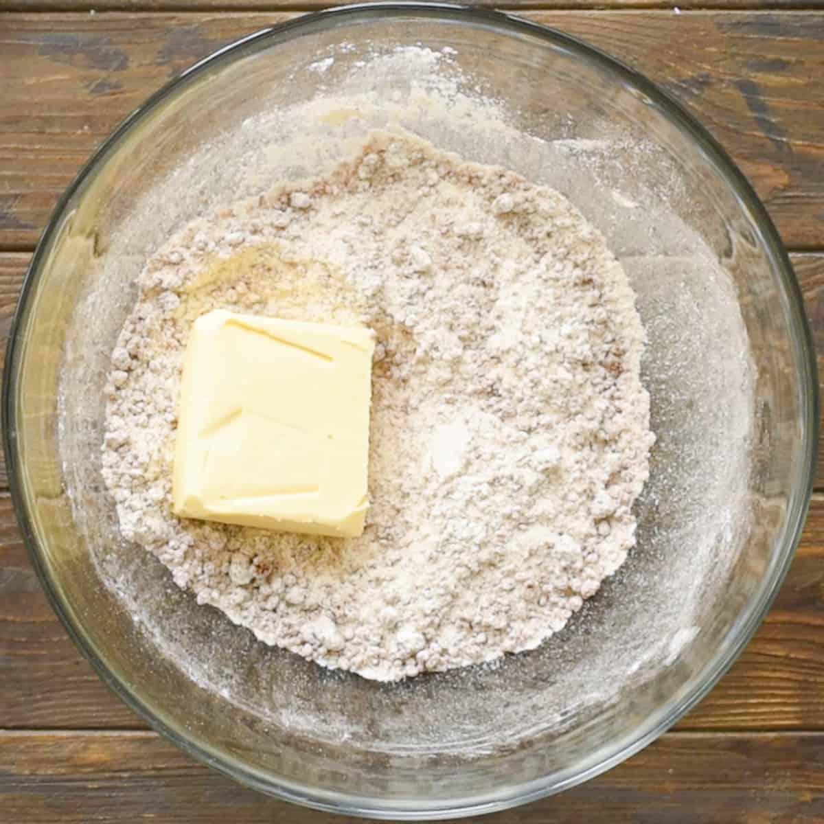 Adding butter to flour sugar mixture for apple brown betty recipe.