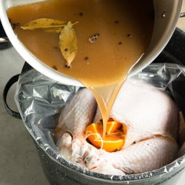 pouring apple cider turkey brine over turkey.