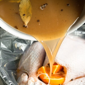 pouring apple cider turkey brine over turkey.