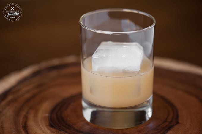 A close up of a half filled glass of apple cider with ice