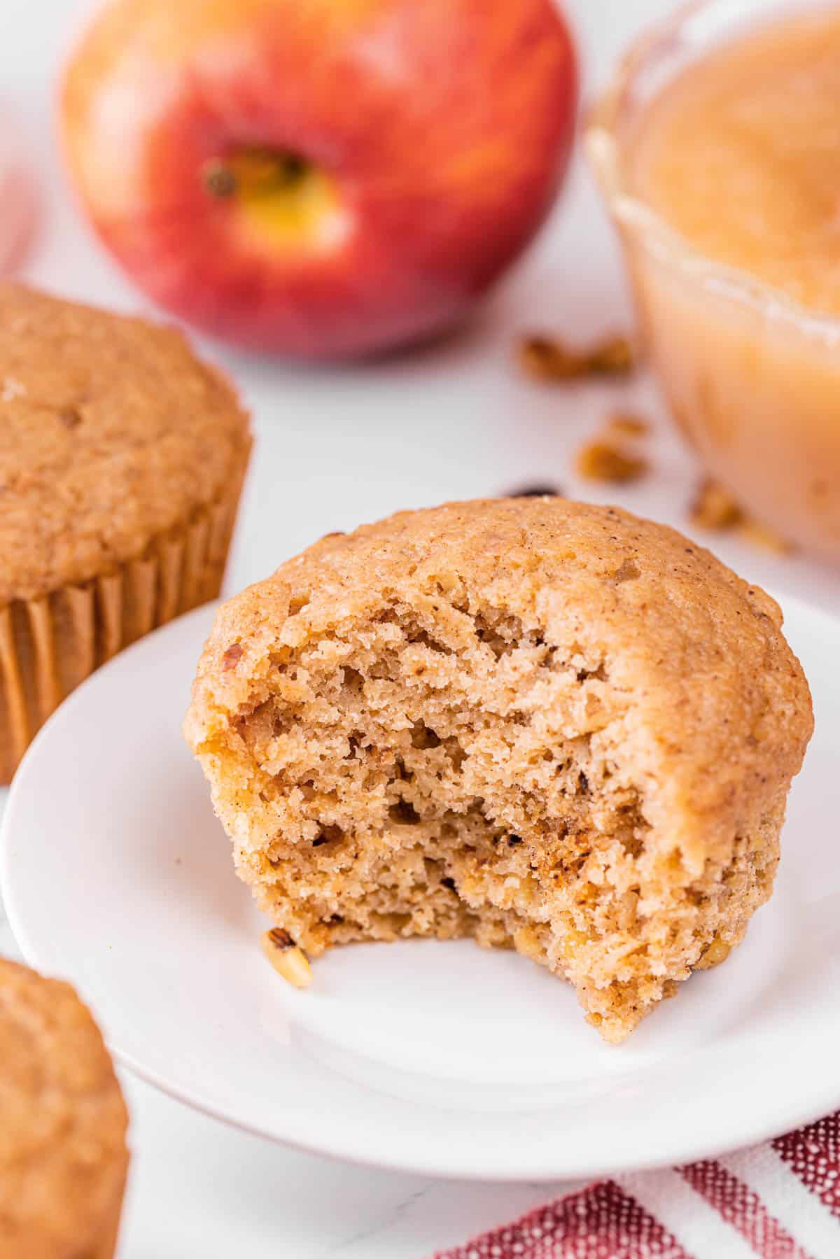 homemade applesauce muffins with bite taken out on plate.