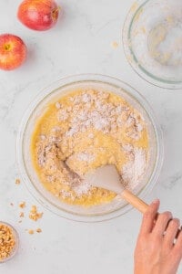 Mixing applesauce muffin batter in bowl.