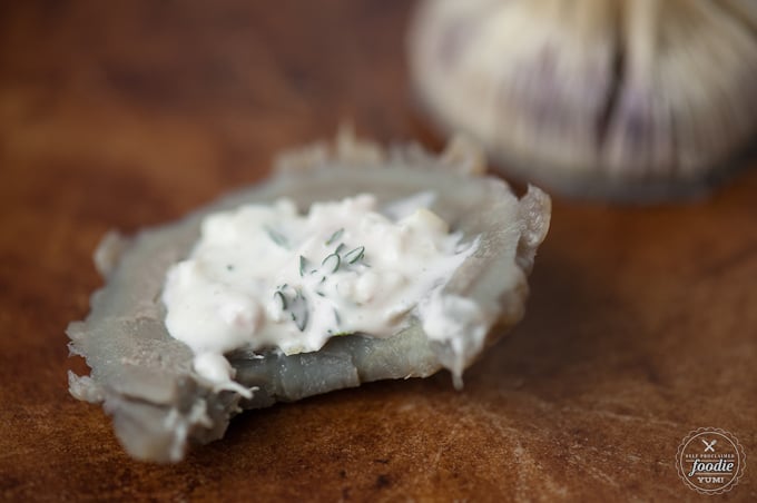 A close up of a piece of artichoke with artichoke dipping sauce on it
