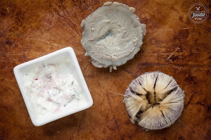 parts of an artichoke with dipping sauce on a table