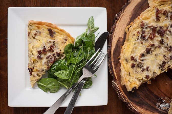 A plate of Quiche Lorraine with greens on the side