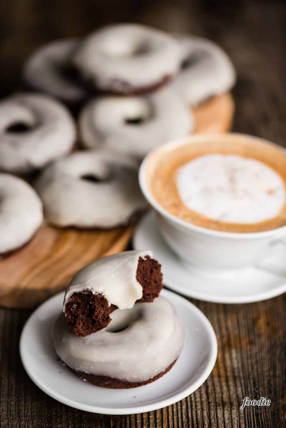 baked chocolate glazed donuts with coffee in the background
