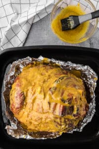 a baked ham in foil with a pineapple mustard brown sugar glaze.