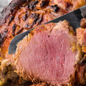 slicing a whole glazed ham that was baked in the oven.