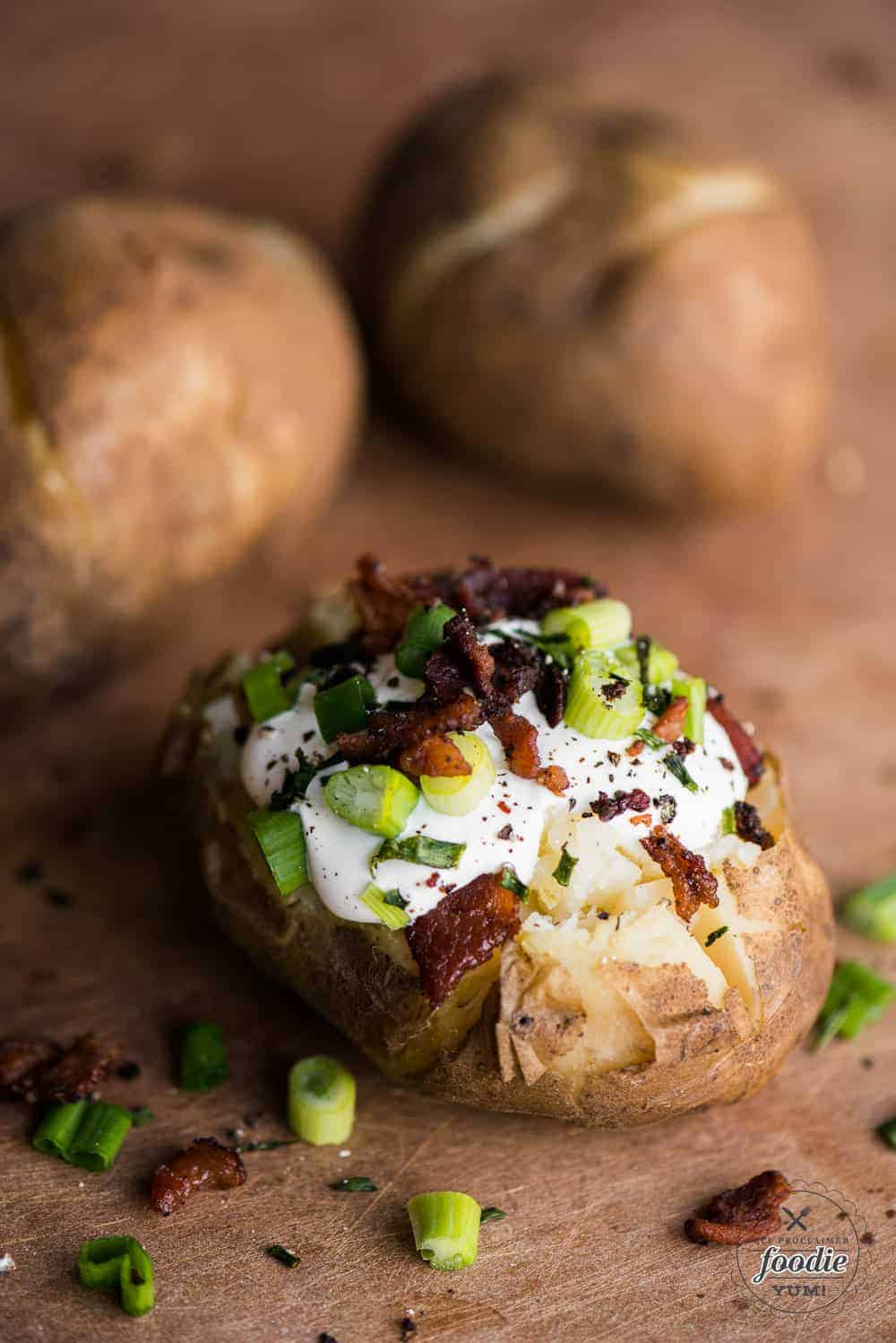 baked potato topped with sour cream, bacon and green onions
