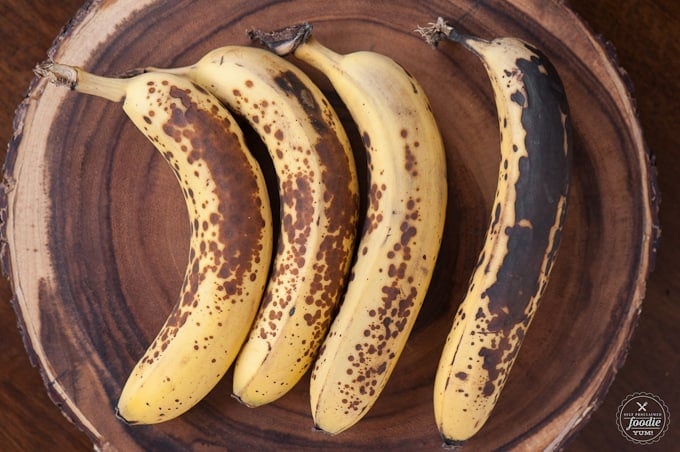 four very ripe bananas on wood platter