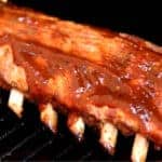 baby back ribs on grill with BBQ sauce