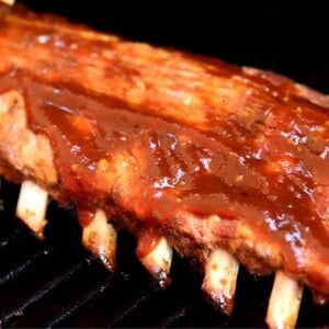 baby back ribs on grill with BBQ sauce