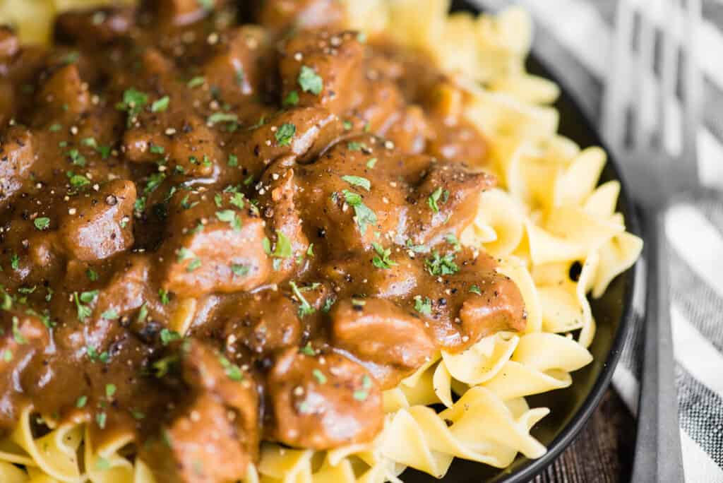 plate of butter noodles with beef stew meat and gravy