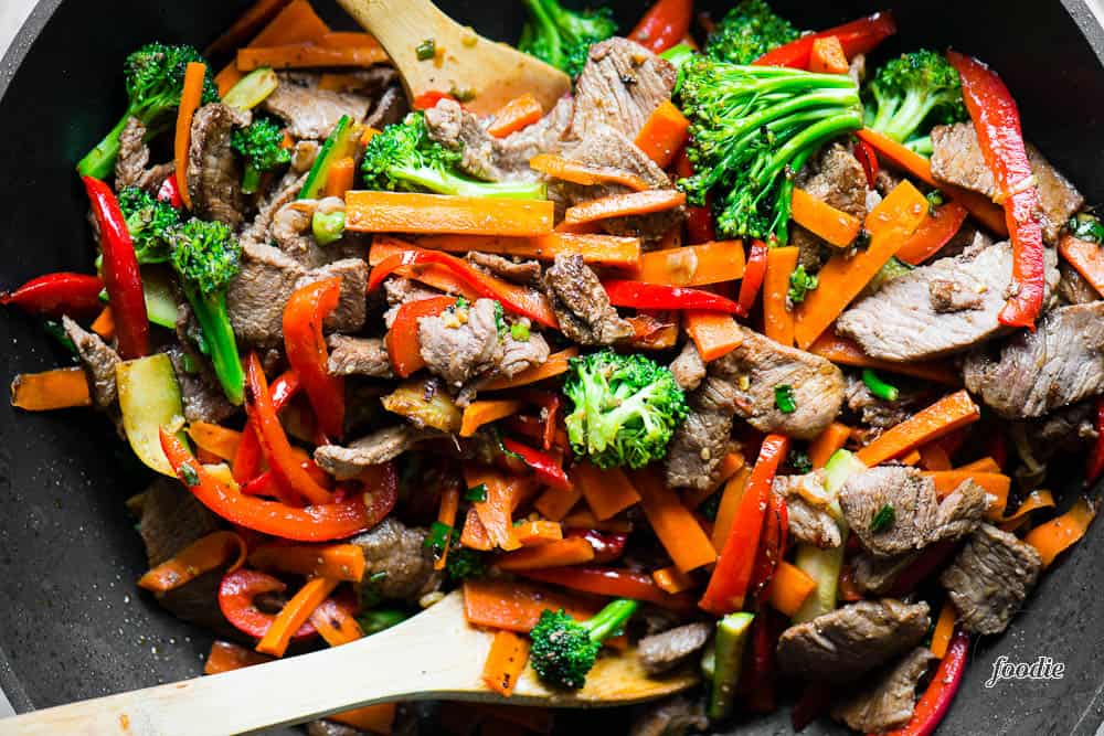 top view of Beef Stir Fry with vegetables in wok with wooden spoons