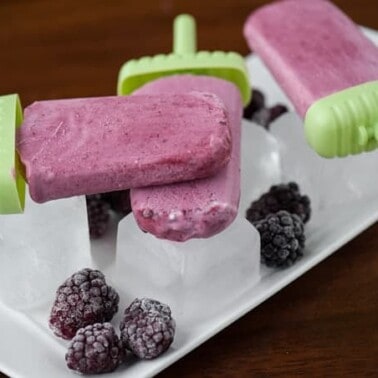 blackberry cream popsicles with ice cubes and frozen berries