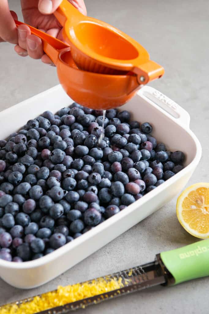 squeezing lemon juice onto fresh blueberries