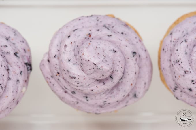 a close up of blueberry cream cheese frosting swirled on a cupcake