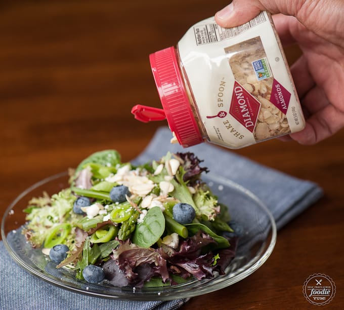 nuts being poured onto a salad