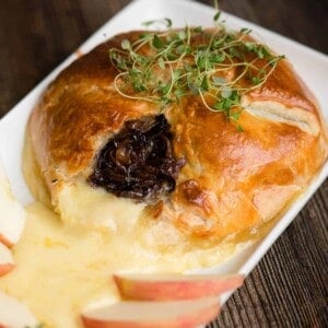 Baked Brie en Croûte with Caramelized Onion on platter with apple slices