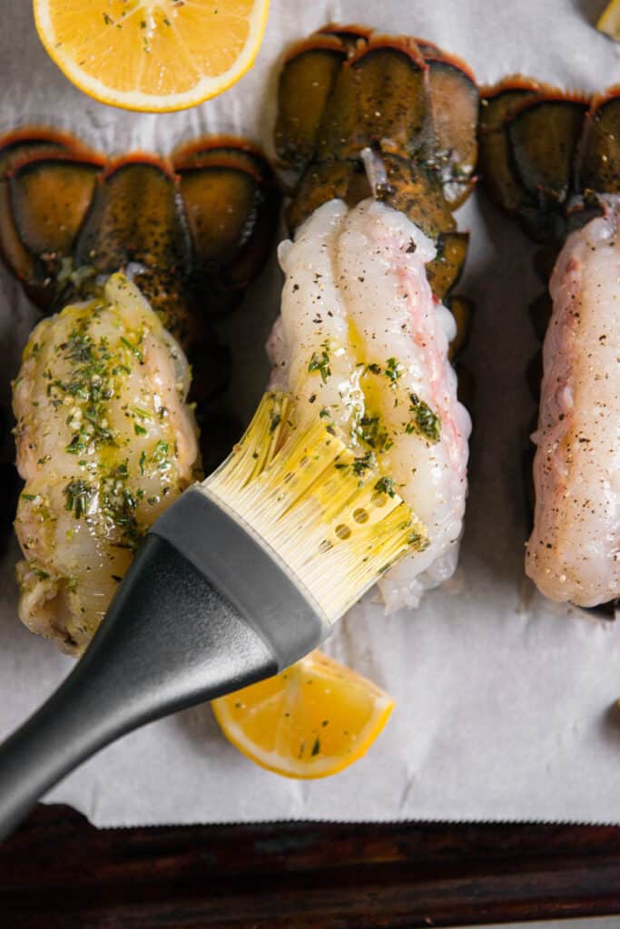 brushing melted garlic herb butter on top of lobster shell